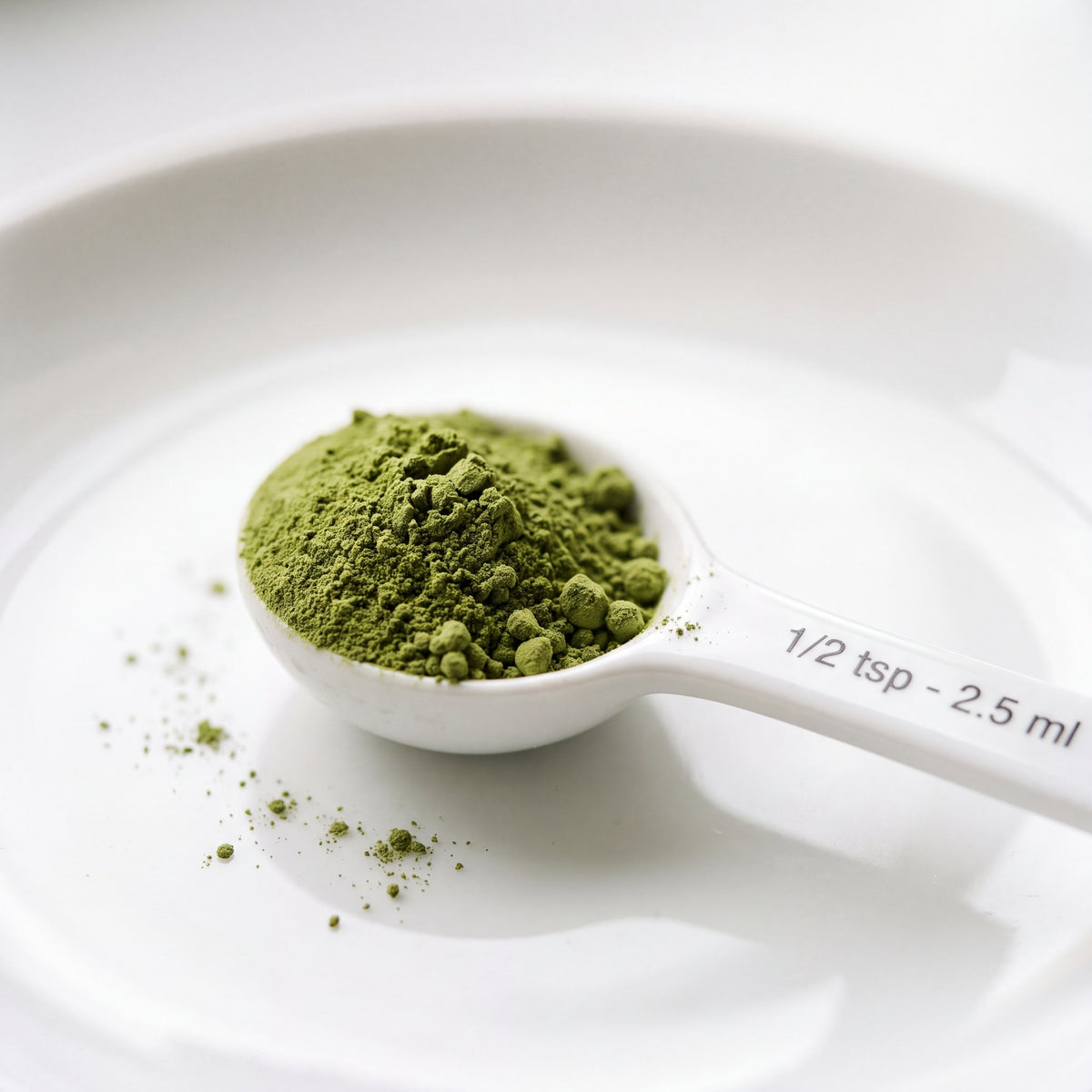 Fine green dog dental powder in a half-teaspoon measuring scoop