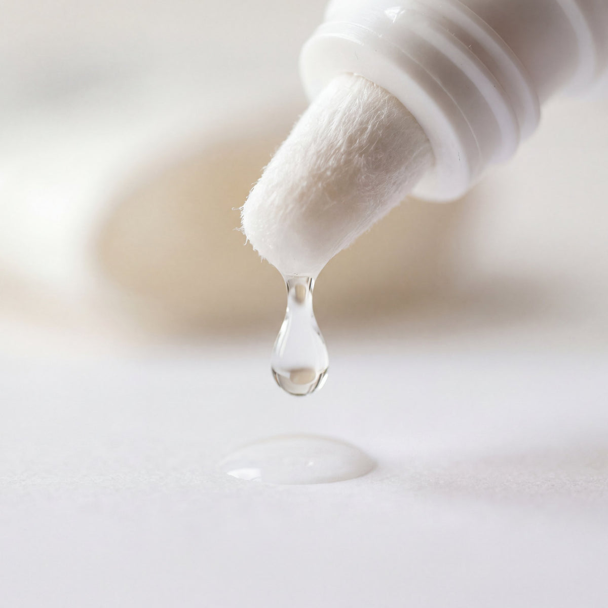 Drop of clear ear cleaning solution falling from the soft nozzle